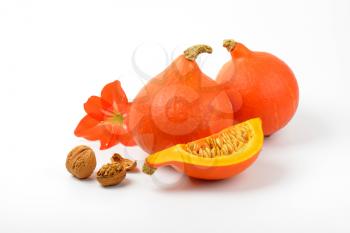 orange pumpkins with walnuts and hibiscus flower on white background