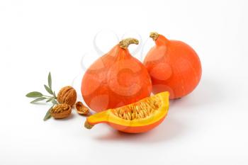 orange pumpkins with walnuts and sprig of sage on white background