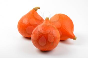 three small orange pumpkins on white background