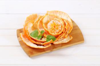 peeled tangerine arranged in peels on wooden cutting board