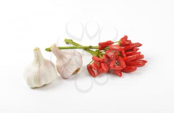 Bunch of small red chili peppers and garlic bulbs on white background
