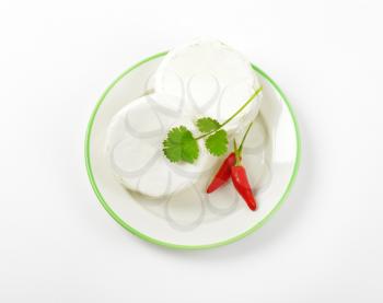Wheels of soft white cheese and red chili peppers on plate