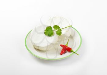 Wheels of soft white cheese and red chili peppers on plate