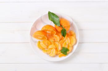 whole and sliced tangerines on white plate