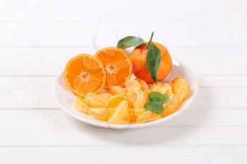 whole and sliced tangerines on white plate