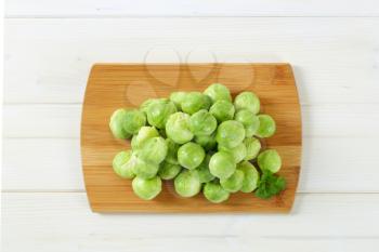 heap of raw Brussels sprouts on wooden cutting board