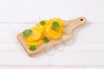 pile of peeled orange slices on wooden cutting board