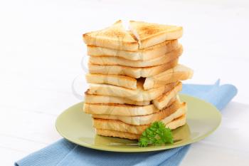 stack of toasted bread slices on green plate - close up