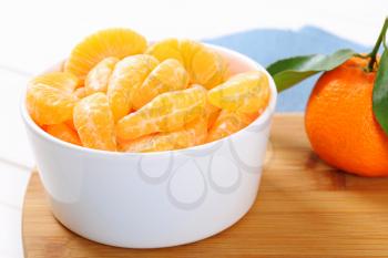 whole ripe tangerine with peeled slices in bowl - close up