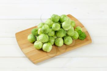 heap of raw Brussels sprouts on wooden cutting board