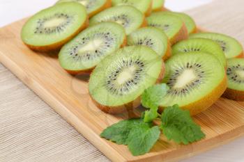 slices of ripe kiwi arranged on wooden cutting board - close up