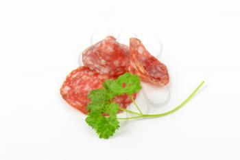 thin slices of salami with parsley on white background