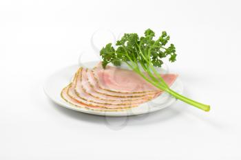 slices of asparagus coated ham with parsley on white plate