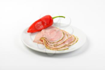 slices of asparagus coated ham with red pepper on white plate