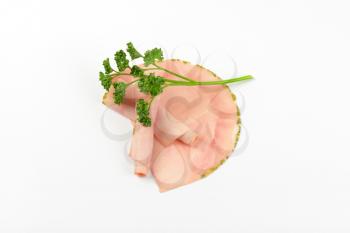 slices of asparagus coated ham with parsley on white background