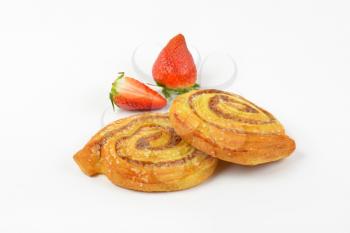 sweet cinnamon rolls and strawberries on white background