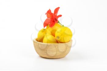 bowl of ripe lemons and red hibiscus bloom on white background
