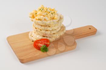 slices of puffed rice bread with scrambled eggs on wooden cutting board