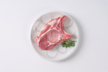 raw pork chop on white plate