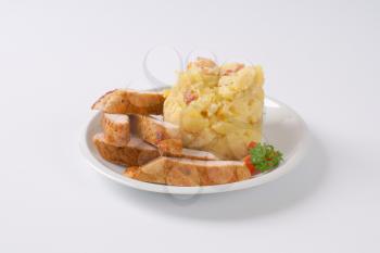 mashed potatoes with sliced roasted pork meat on white plate