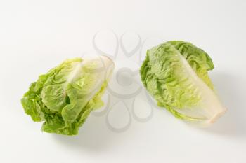 two heads of little gem lettuce on white background
