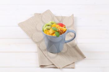 cup of corn flakes with milk and fresh fruit on beige place mat