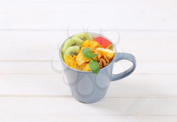 cup of corn flakes with milk and fresh fruit on white background