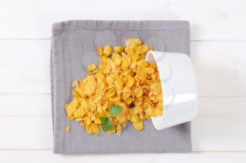pile of corn flakes spilt out on grey place mat