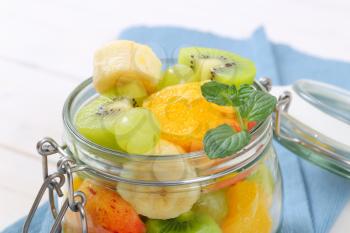 jar of fresh fruit salad on blue place mat - close up