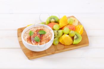 fresh fruit salad with cinnamon yogurt on wooden cutting board