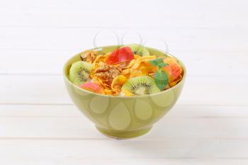 bowl of corn flakes with milk and fresh fruit on white background