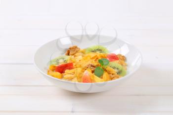 plate of corn flakes with milk and fresh fruit on white background