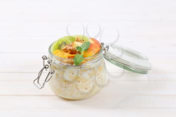 jar of corn flakes with milk and fresh fruit on white background