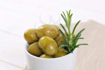 cup of green olives with fresh rosemary - close up