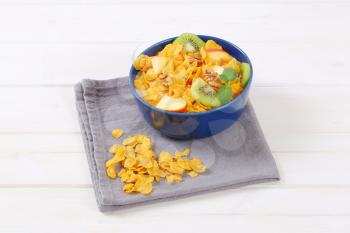 bowl of corn flakes with milk and fresh fruit on grey place mat