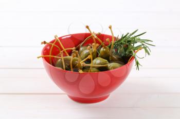 bowl of pickled caper berries on white wooden background