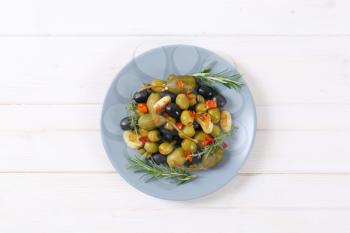 Plate of green and black olives with garlic, capers and caper berries