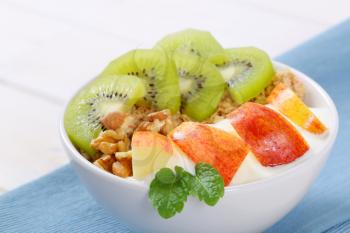 bowl of muesli with yogurt and fresh fruit on blue place mat - close up
