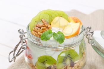 jar of muesli with yogurt and fresh fruit - close up