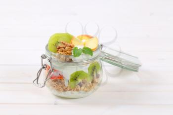 jar of muesli with yogurt and fresh fruit on white background