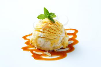 Scoop of yellow white ice cream with caramel sauce