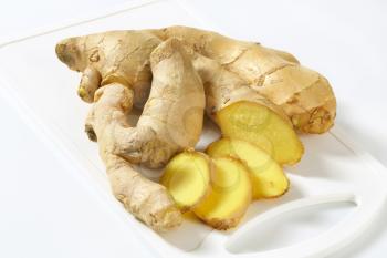 Fresh ginger root on white plastic cutting board