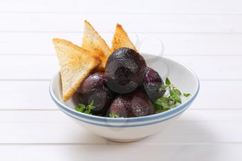 bowl of baked whole beet with toast on white wooden background