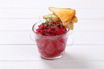 glass of fresh beetroot puree with toast on white wooden background