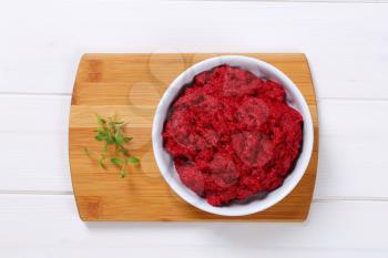 bowl of fresh beetroot puree on wooden cutting board