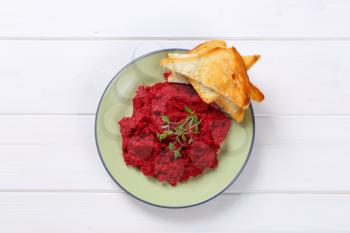 plate of fresh beetroot puree with toast on white wooden background