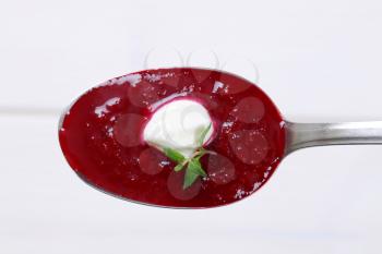 spoon of beetroot cream soup on white background