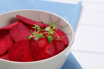 bowl of thin beetroot slices on blue place mat - close up
