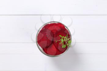 glass of thin beetroot slices on white wooden background