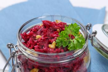jar of fresh beetroot spread with walnuts on blue place mat - close up